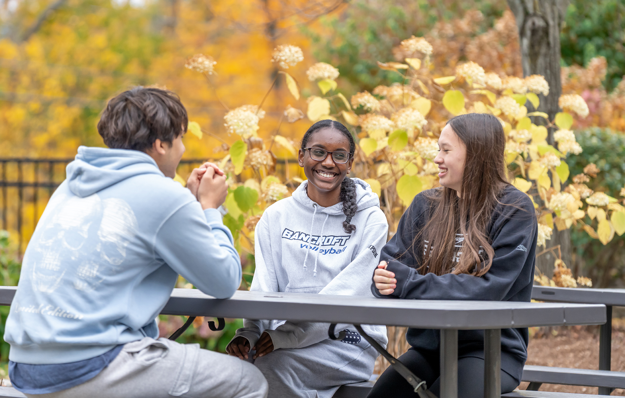 Students sitting around a table outside, laughing.