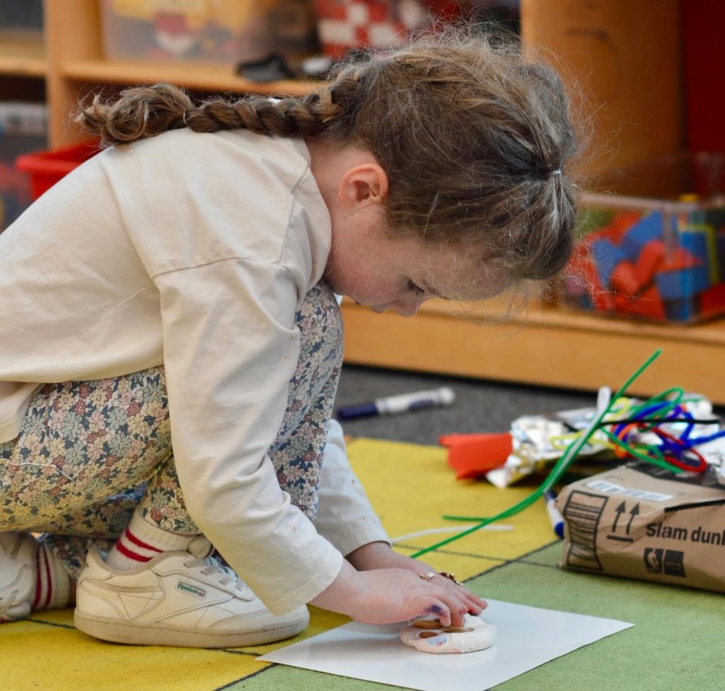 Lower school student on floor working on project.