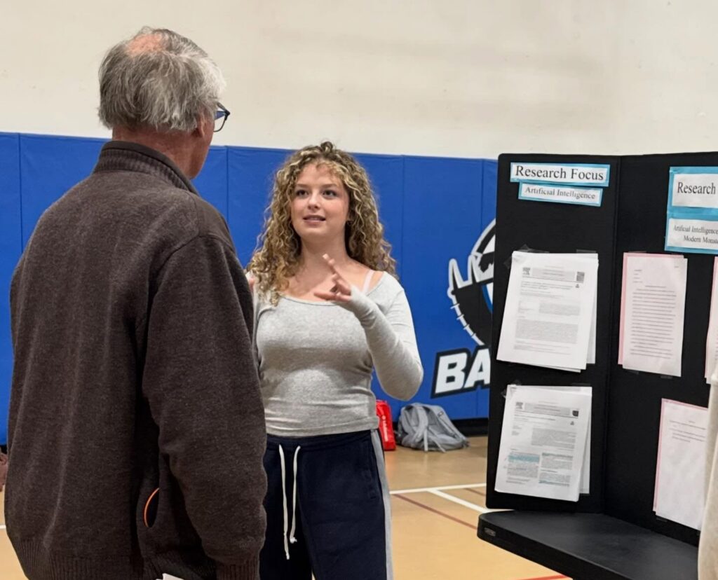 Student explaining their research project to an observer.