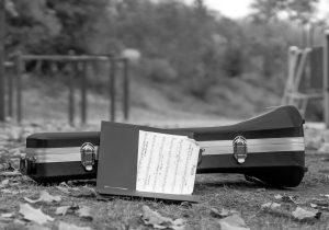 A black nad white photo of a trumpet case and a folder of sheet music on the playground at Bancroft School in Worcester.