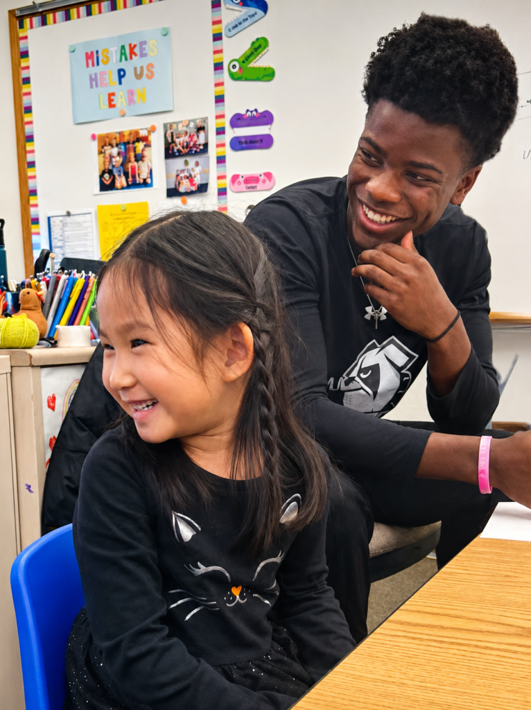 A Bancroft School Upper School and a Lower School student laugh together during bulldog bonding.
