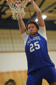 Student on basketball court dunking a ball.