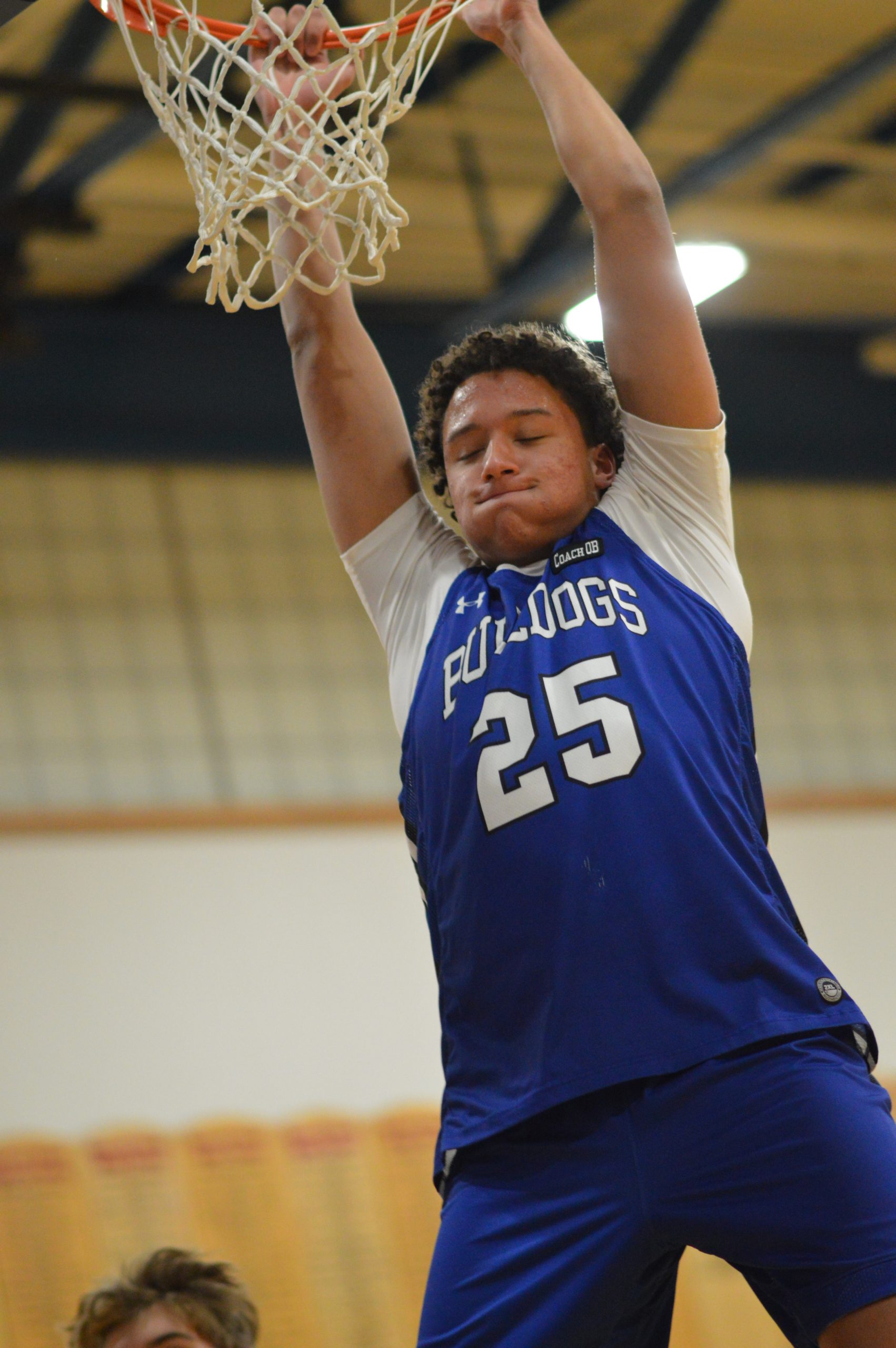 Student on basketball court dunking a ball.