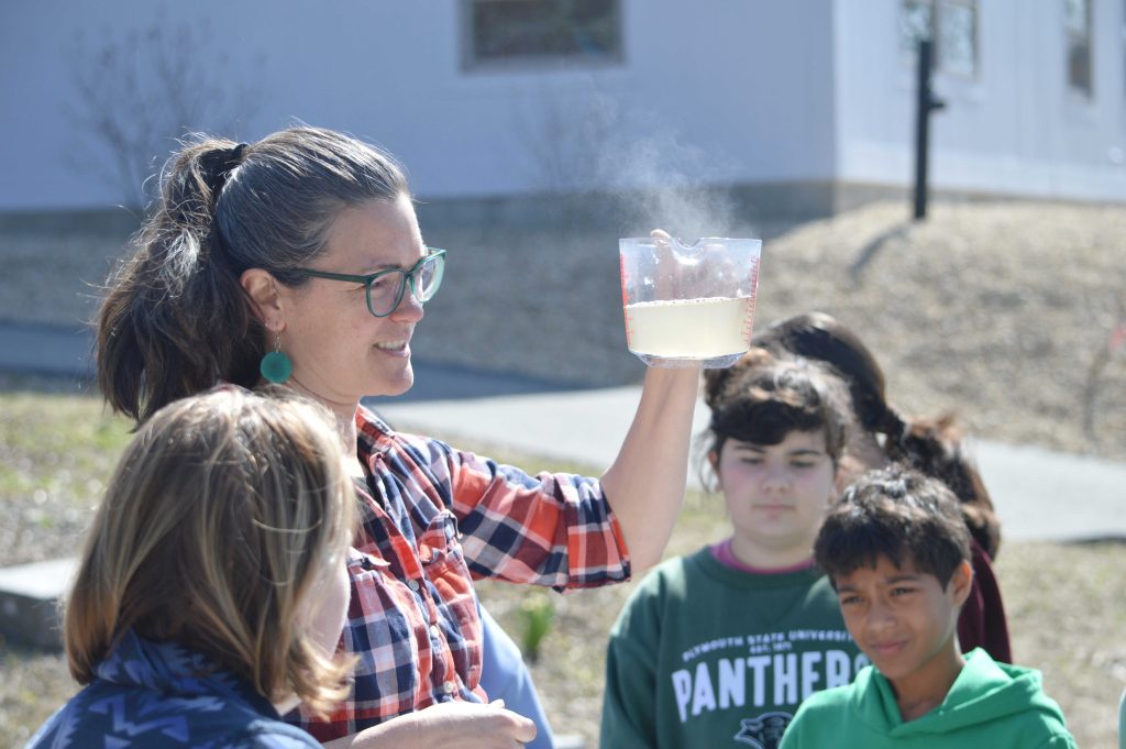 Teacher holding measuring cup of sap.
