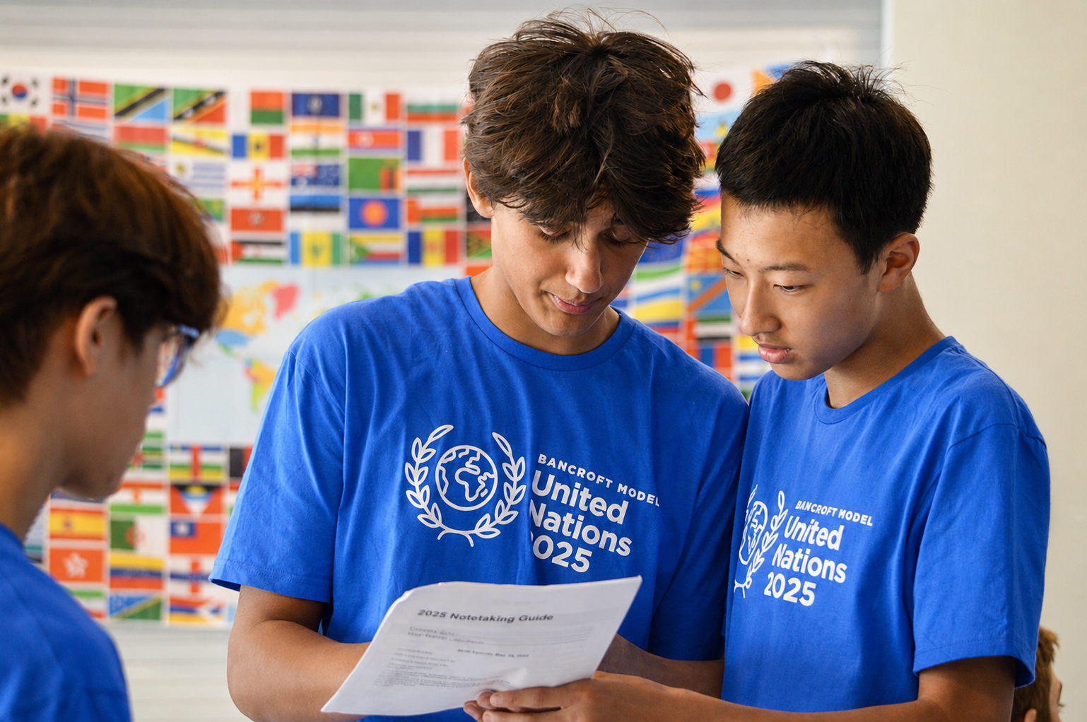 Middle School students at Bancroft School in Worcester, MA wearing Model UN t-shirts looking over paperwork.