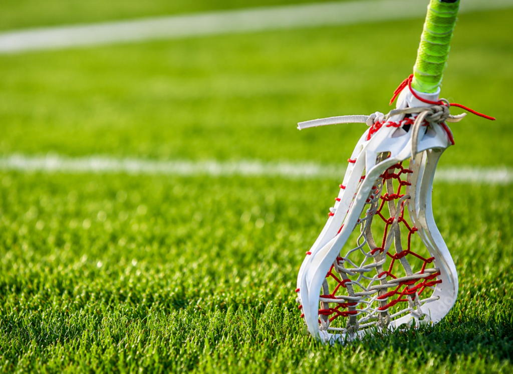 Girls lacrosse stick on a grass field.