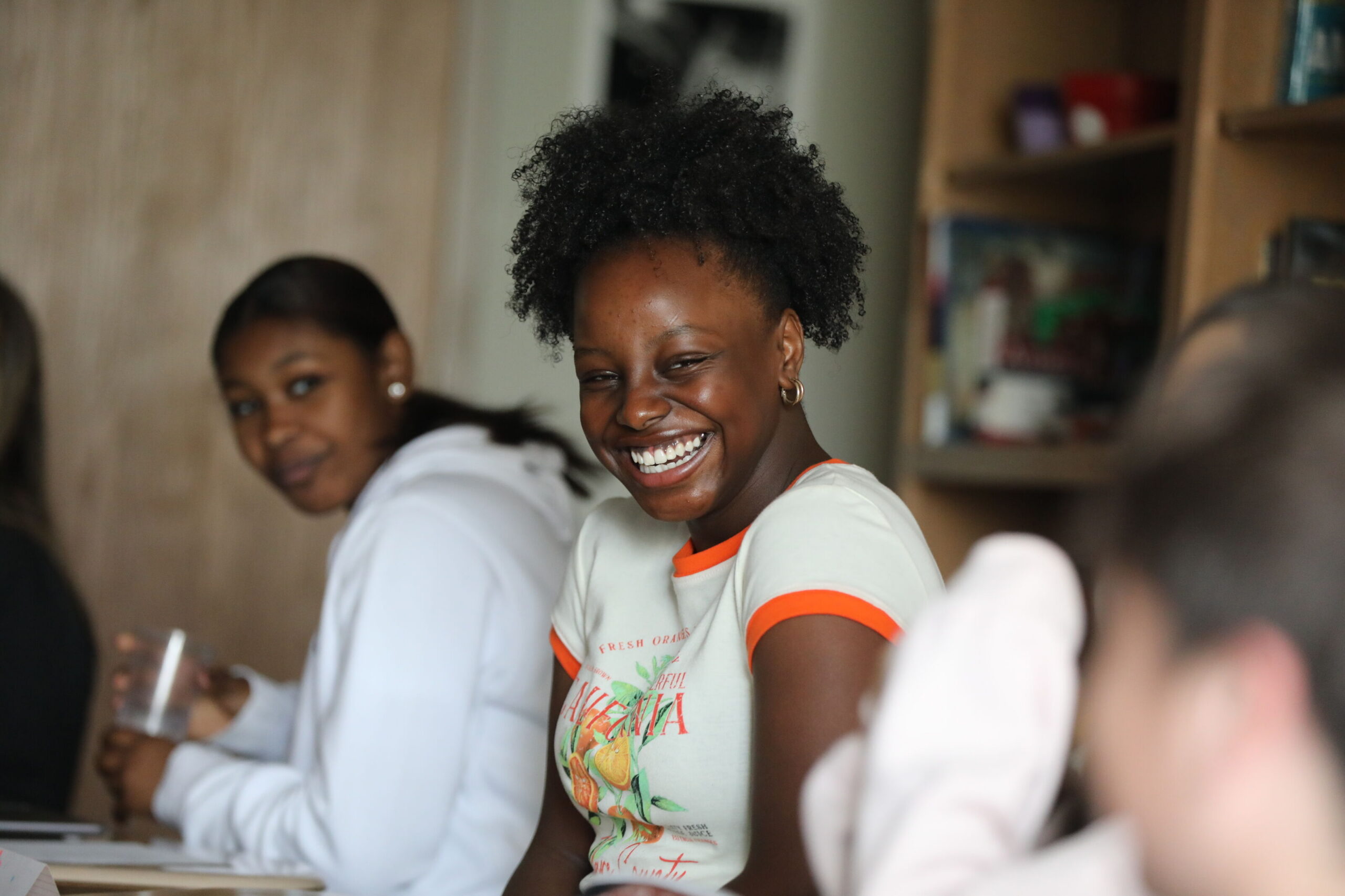 Upper School student sit at desk laughing.