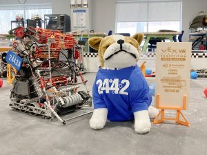 Stuffed bulldog with a Robodogs shirt on sitting next to an award.