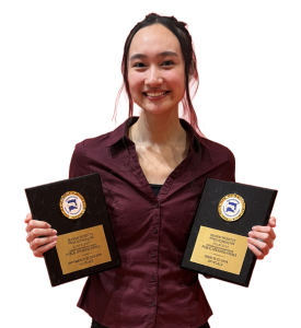Student standing with awards.