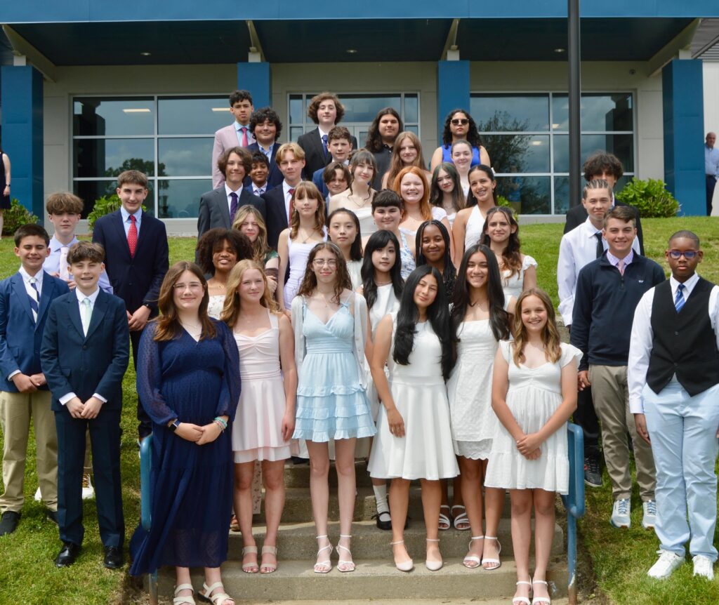 Middle School students standing on stairs posing. for a photo.